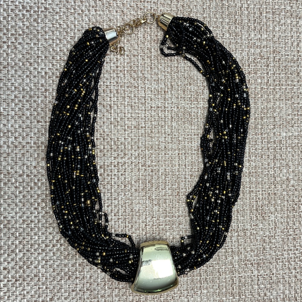 23 strand black seed bead necklace; copper accents. Gold focal slide. Weighted